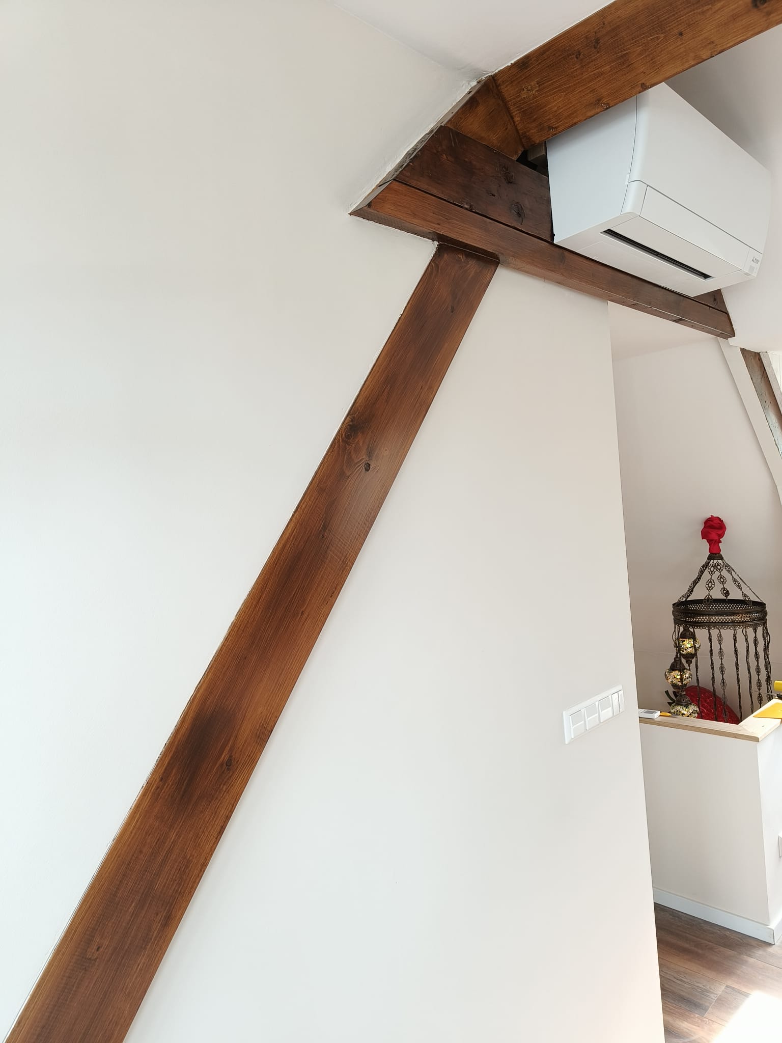 Witte wandafwerking rond zichtbare houten dakbalken