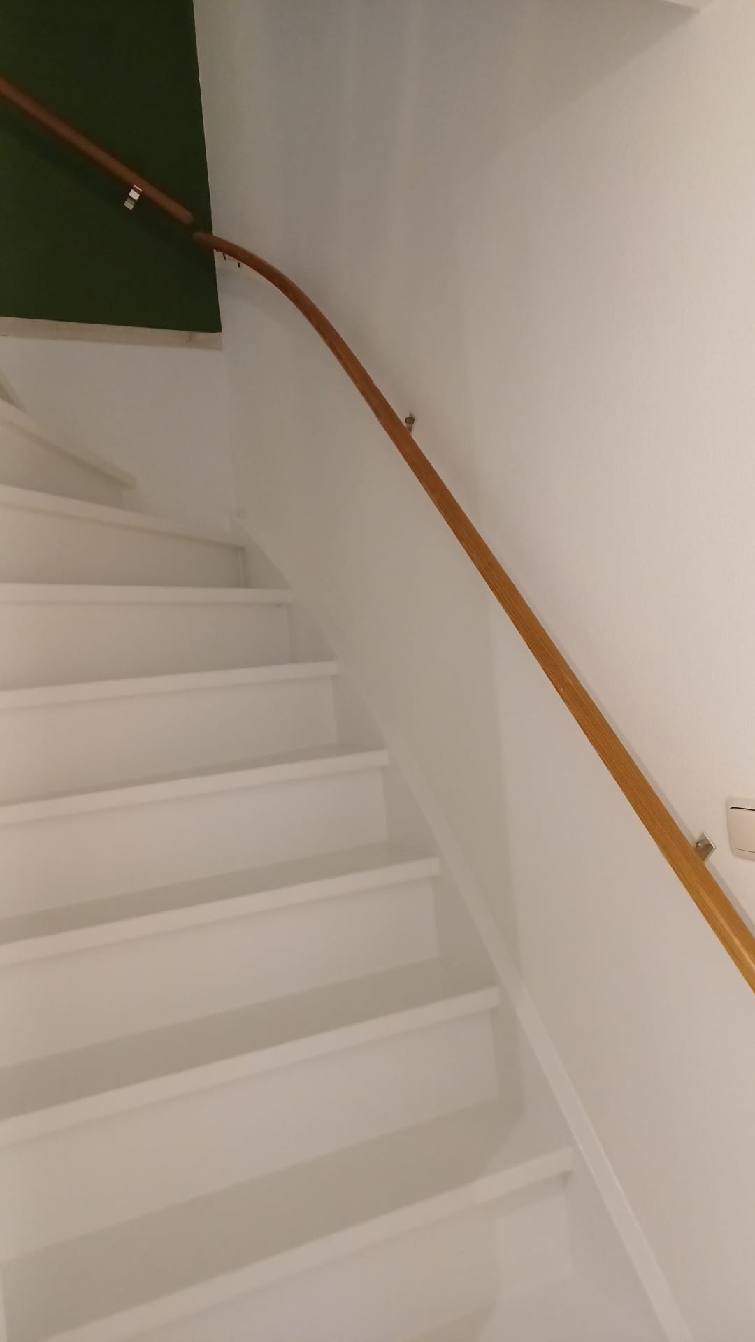 Wit geschilderde trap met houten leuning en lichte wandafwerking
